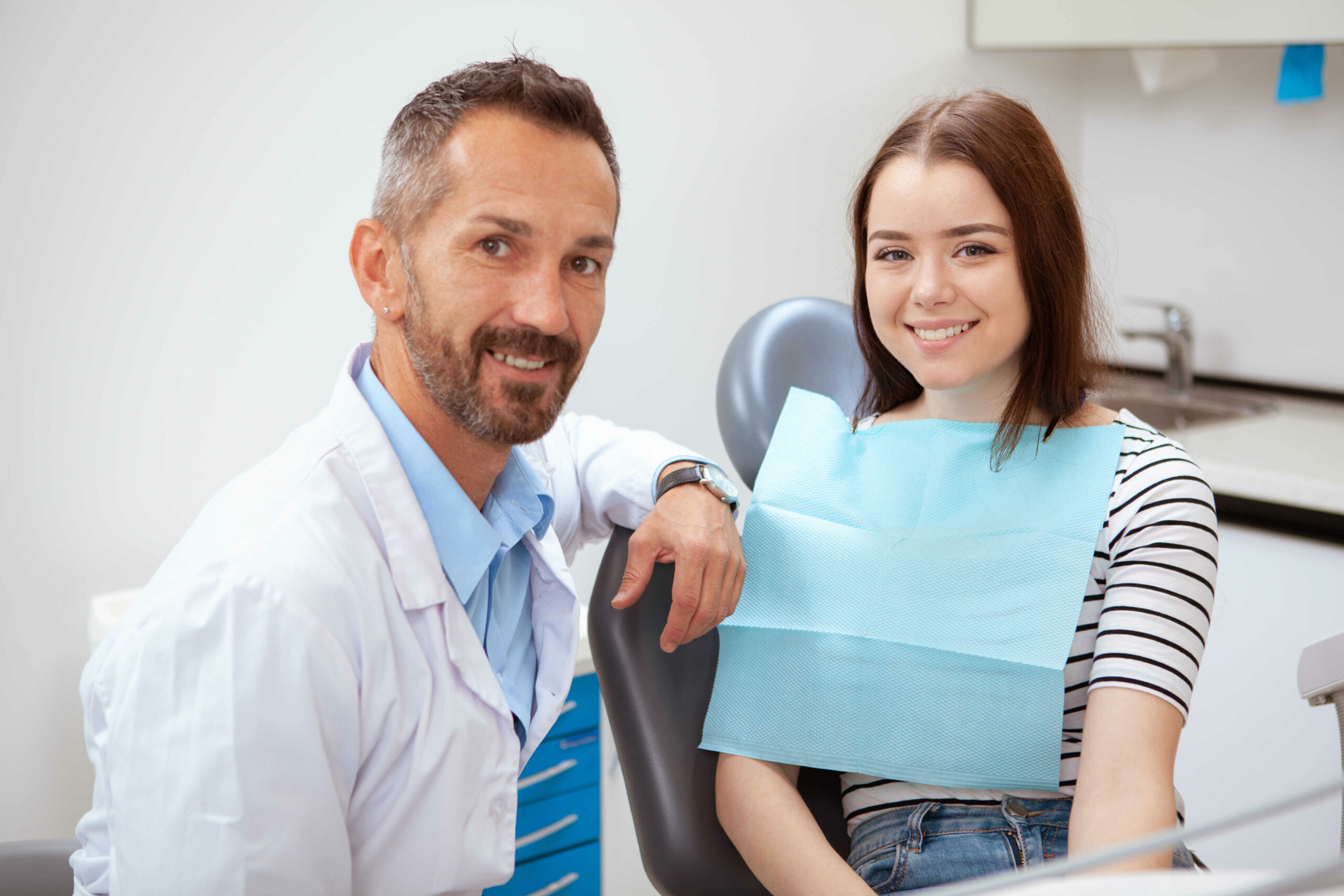 handsome-mature-male-dentist-and-his-charming-female-patient-smiling-to-the-camera-after-medical-examination-in-chicago