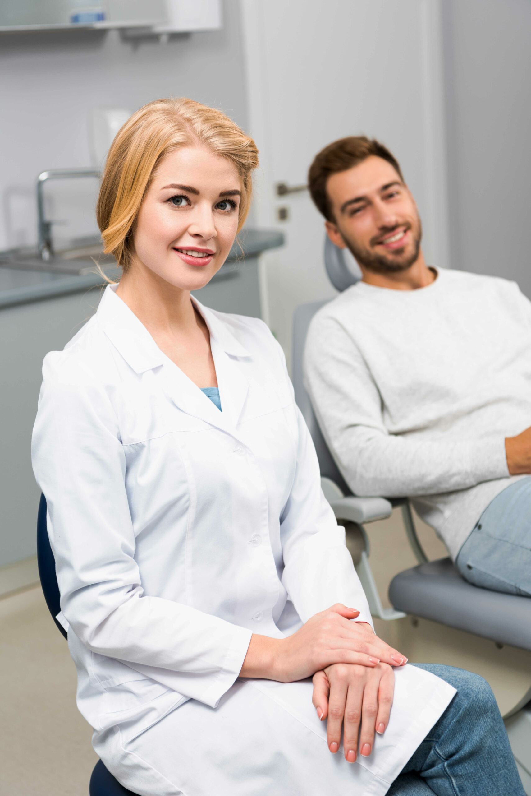 happy-female-dentist-and-handsome-young-client-looking-at-camera-in-dentist-office-in-chicago