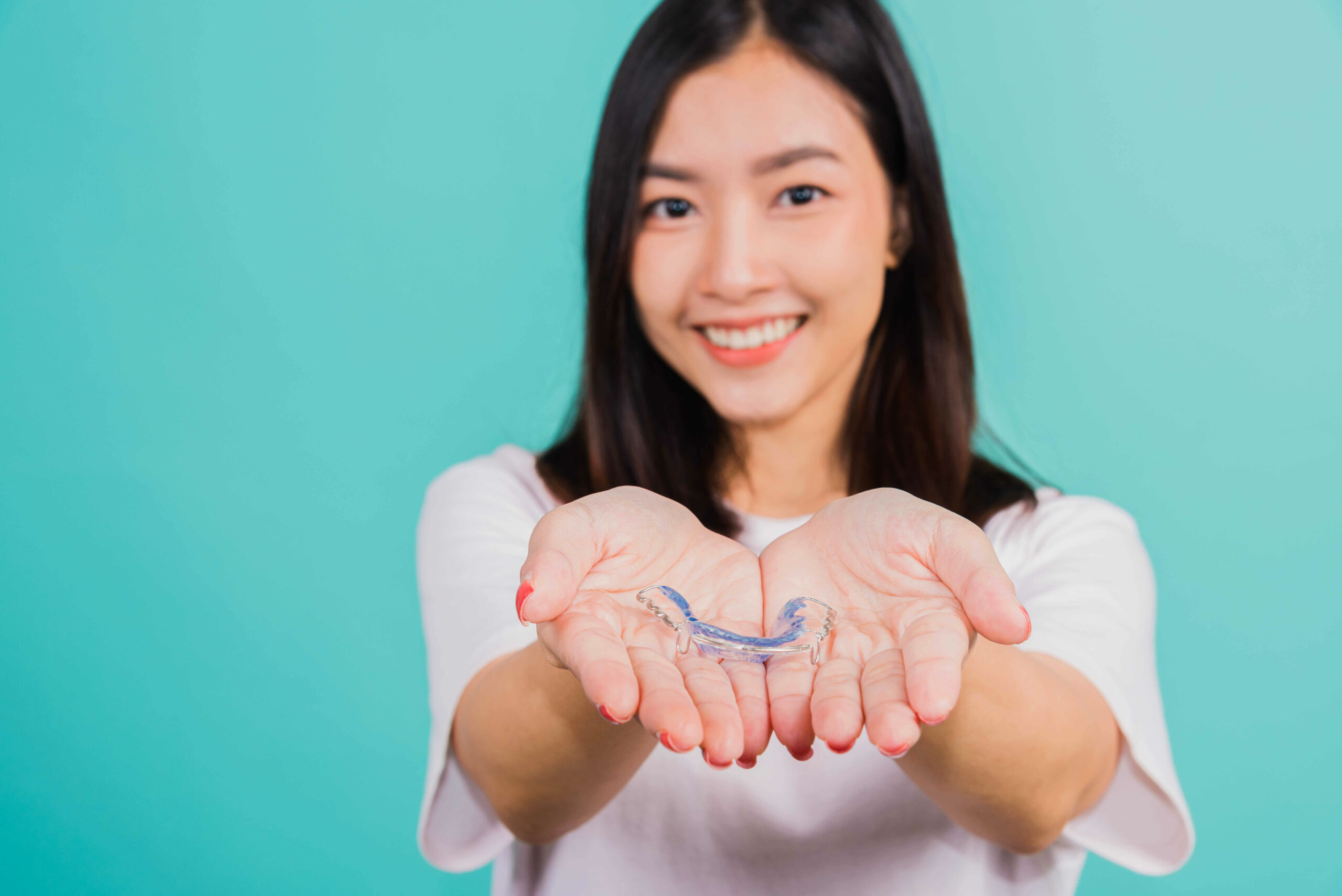 portrait-young-asian-beautiful-woman-smiling-holding-silicone-orthodontic-retainers-for-teeth-on-hand-palm-in-chicago