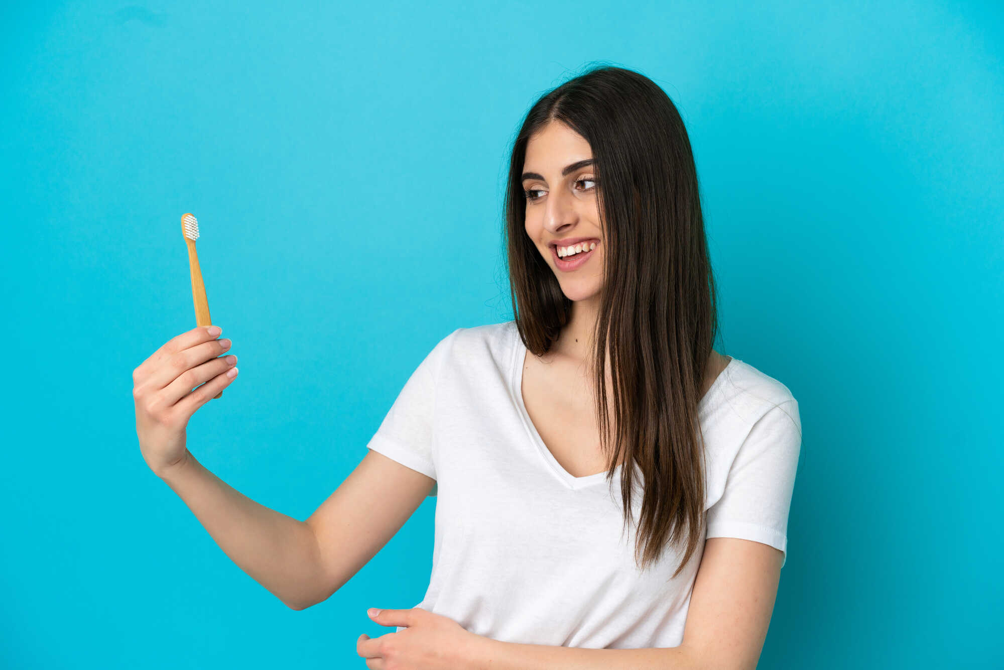 young-caucasian-woman-brushing-teeth-isolated-on-blue-background-with-happy-expression-in-chicago